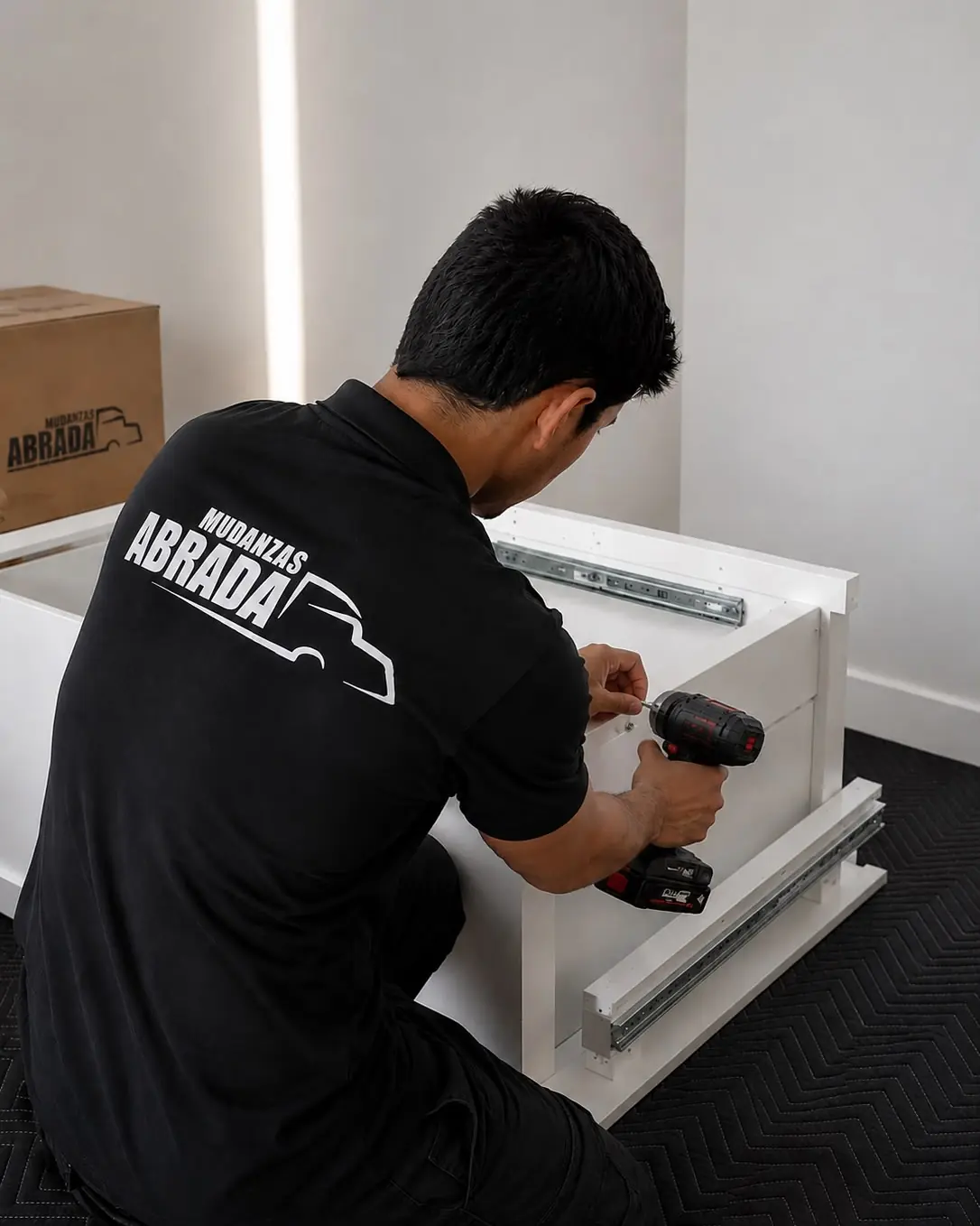 Operario de Mudanzas Abrada montando una cajonera con atornillador eléctrico en el domicilio del cliente
