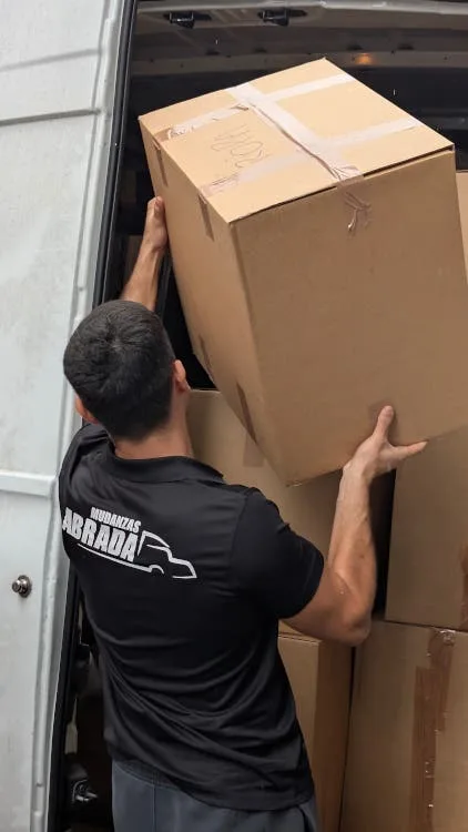 Operario de Mudanzas Abrada cargando una caja grande de carton en la furgoneta